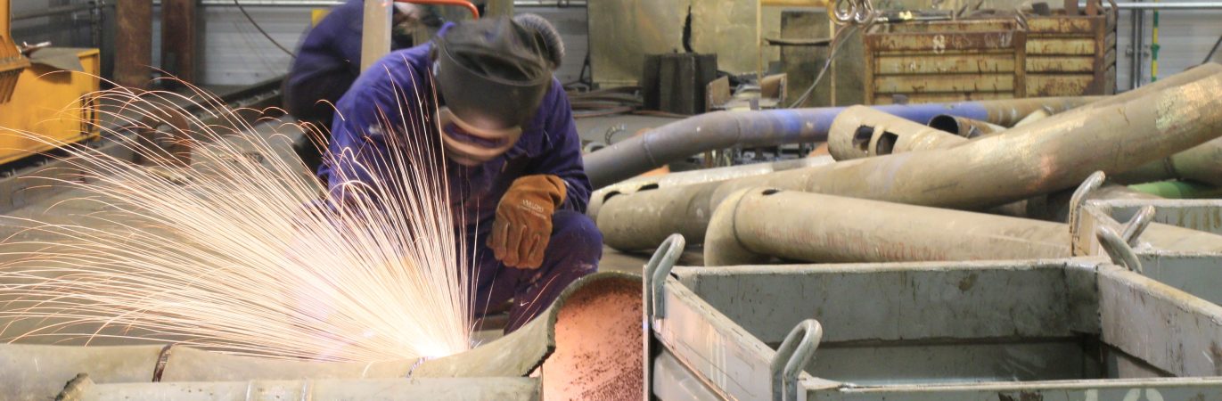 Darbuotojas Ignalinos atominėje elektrinėje pjauna metalinį vamzdį suvirinimo įranga.
