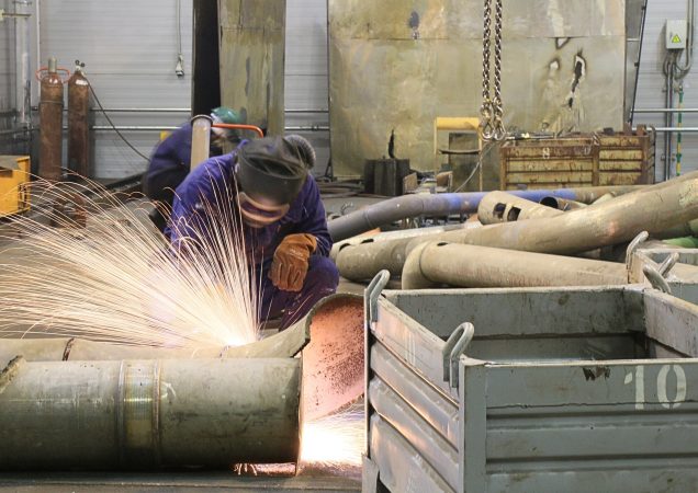 Ignalinos atominės elektrinės darbuotojas pjauna metalinius vamzdžius suvirinimo įranga.