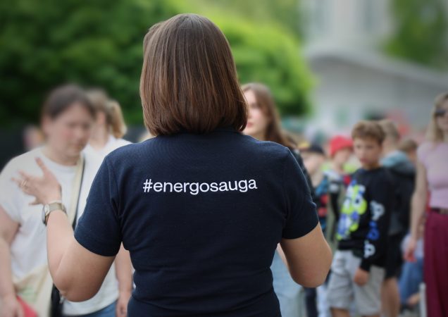 Moteris su marškinėliais „#energosauga“ kalba su žmonėmis viešame renginyje.
