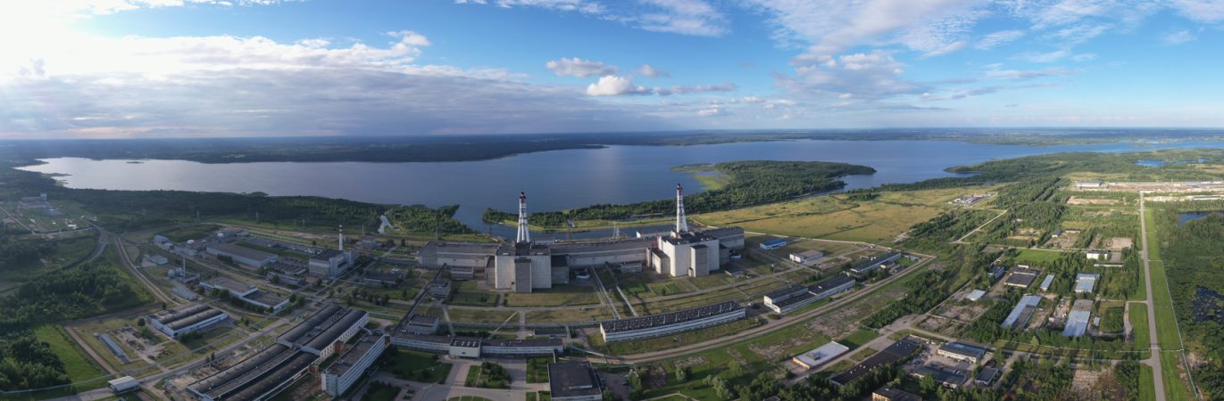 Ignalinos atominės elektrinės panoraminis vaizdas iš oro su matomais pastatais, dviem kaminų bokštais ir šalia esančiu ežeru.