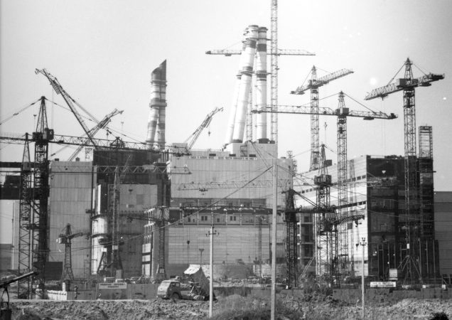 Istorinė nuotrauka – Ignalinos atominės elektrinės statybos aikštelė su daugybe kranų ir nebaigtais reaktorių pastatais.