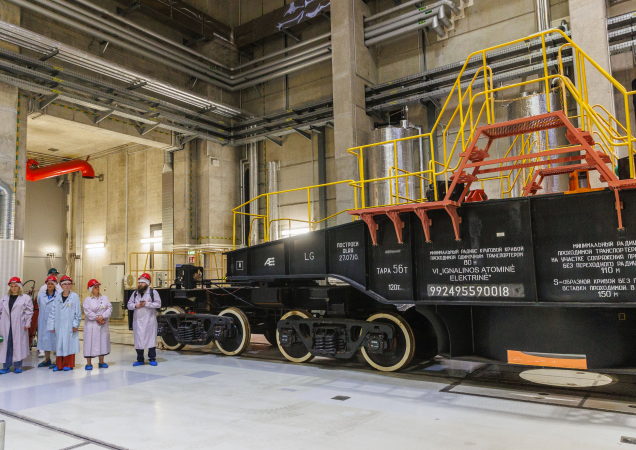 Ignalinos atominės elektrinės darbuotojai su apsauginiais rūbais stovi šalia specialaus radioaktyviųjų atliekų transportavimo vagono pastato viduje.