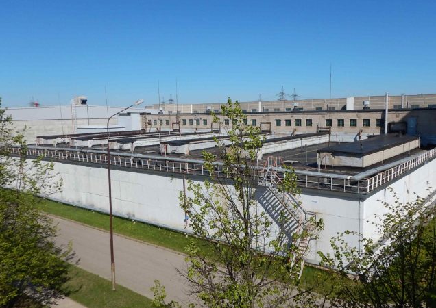 Ignalinos atominės elektrinės bitumuotų atliekų saugyklos pastatas su modernizuotomis konstrukcijomis ir turėklais ant stogo.