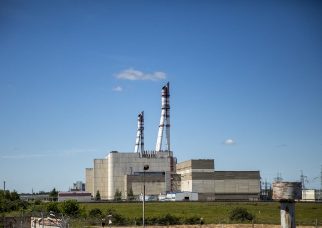 Ignalinos atominės elektrinės pastatų kompleksas su dviem aukštais kaminų, fotografuotas giedrą dieną.
