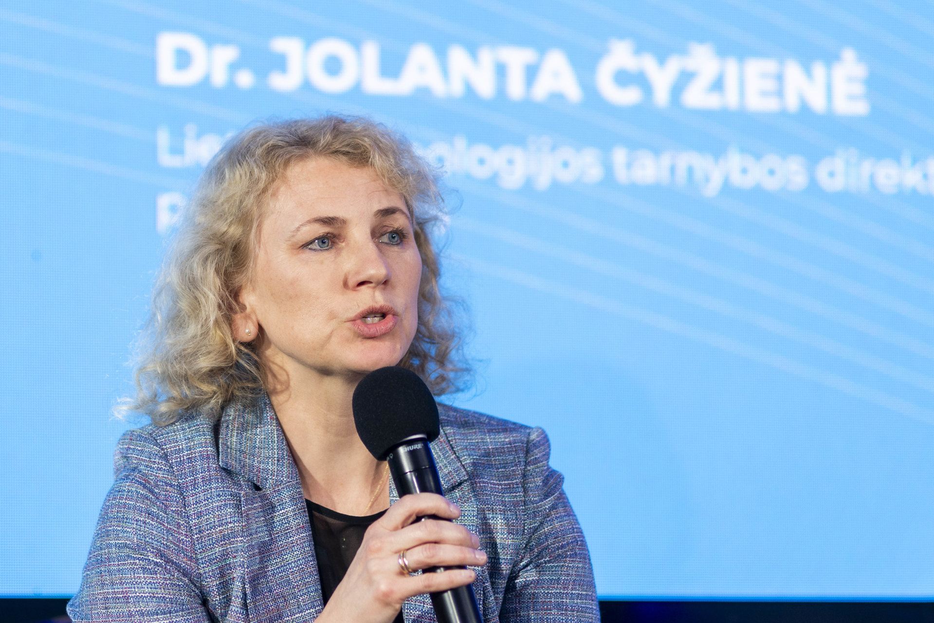 Dr. Jolanta Čyžienė kalba laikydama mikrofoną viešoje diskusijoje ar konferencijoje.