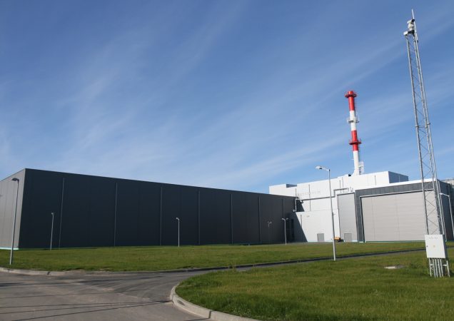 Kietųjų radioaktyviųjų atliekų tvarkymo ir saugojimo komplekso pastatas su raudonai balta dūmų išmetimo kaminu Ignalinos atominėje elektrinėje.