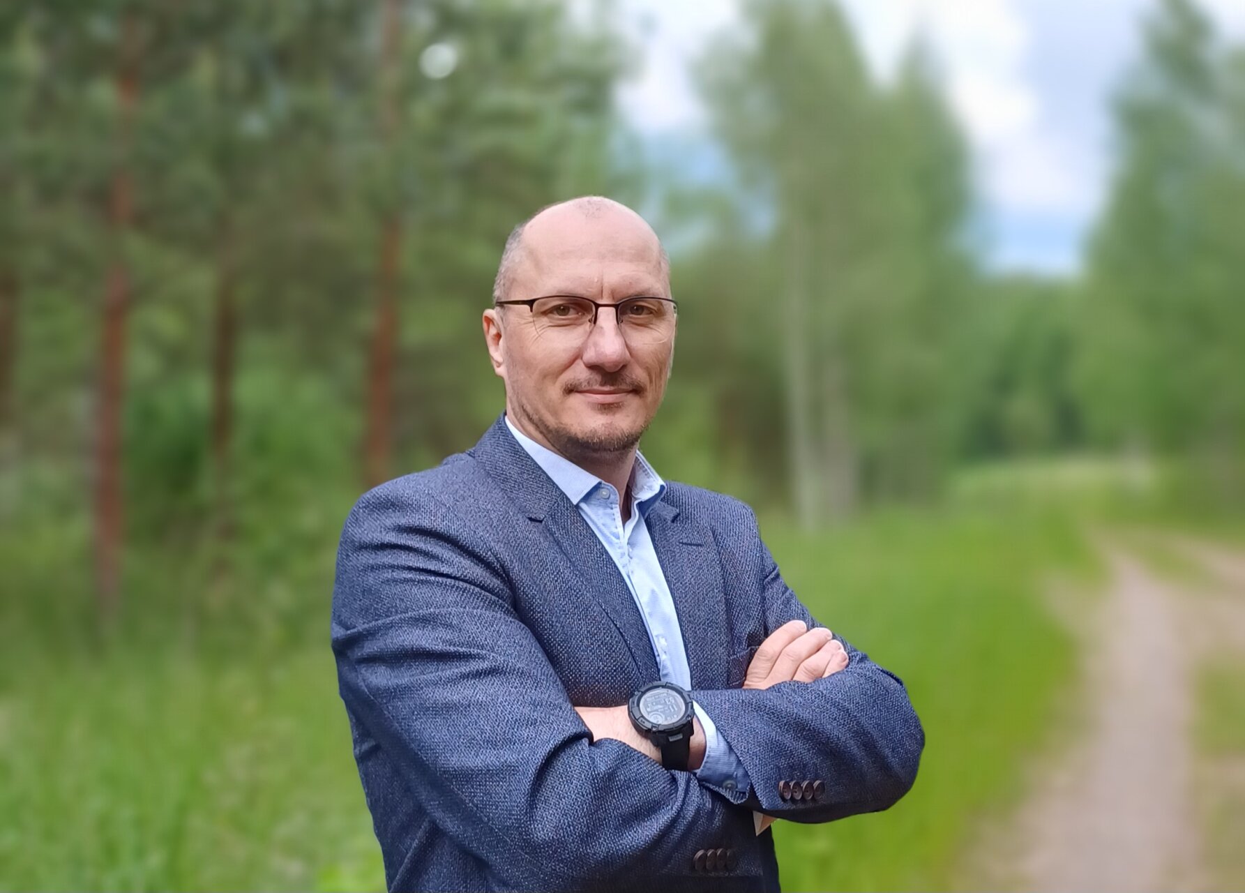 Marius Pernavas stovi lauke miško take, vilki kostiumą ir pozuoja sukryžiavęs rankas.