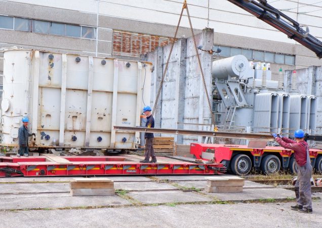 Darbininkai ruošia transformatorių kėlimui ant specialios transportavimo platformos prie Ignalinos atominės elektrinės pastato.
