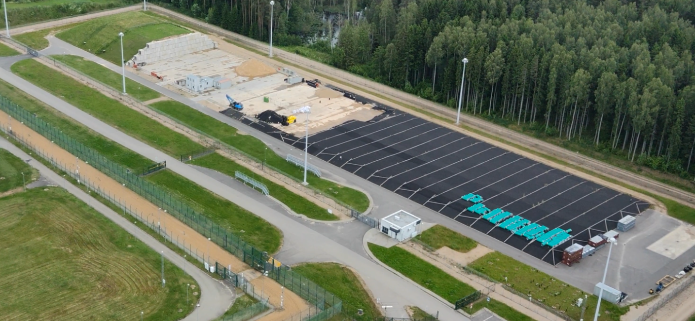 Aeronuotrauka, vaizduojanti labai mažai radioaktyvių atliekų paviršinį atliekyną su juoda danga, apsaugine tvora ir šalia esančiu mišku.