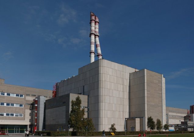 Ignalinos atominės elektrinės pastatai su dviem reaktoriaus bokštais, giedras mėlynas dangus fone.