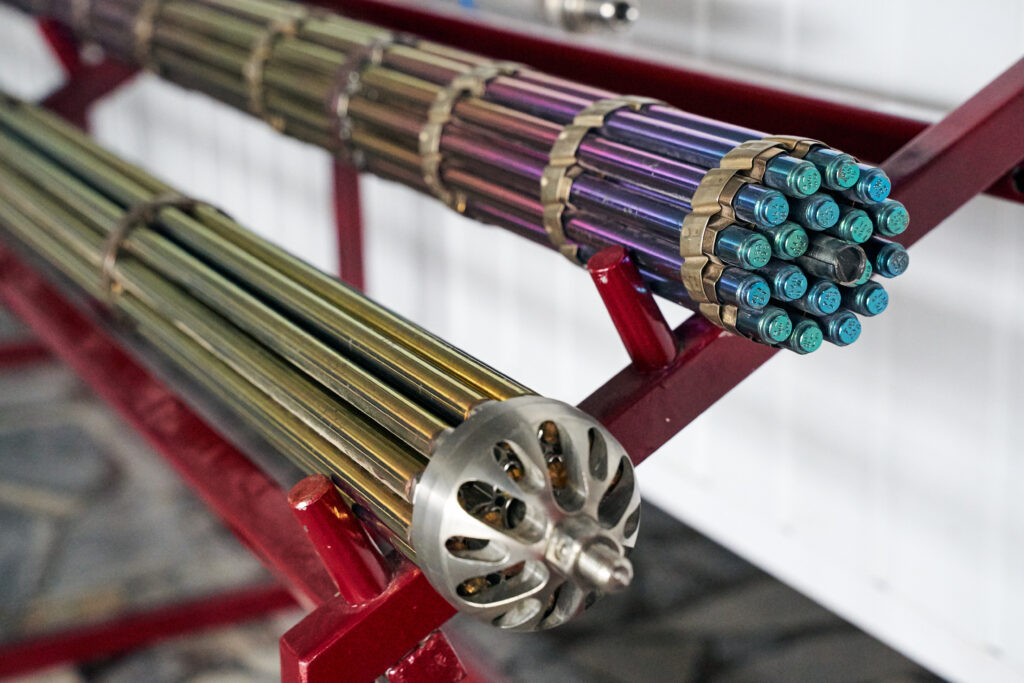 Metalinės kuro kasetės branduolinės elektrinės ekspozicijoje, žvilgančios įvairiomis spalvomis.