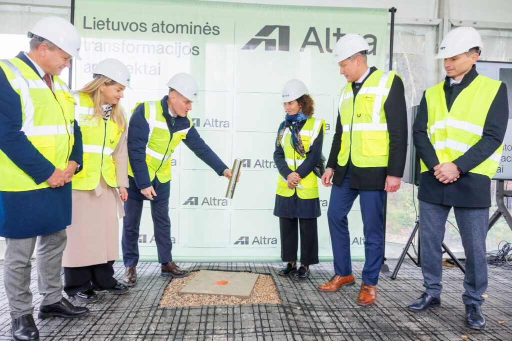 Atliekyno kapsulės įkasimo renginys, matomi įvairių organizacijų atstovai, užkasantys kapsulę