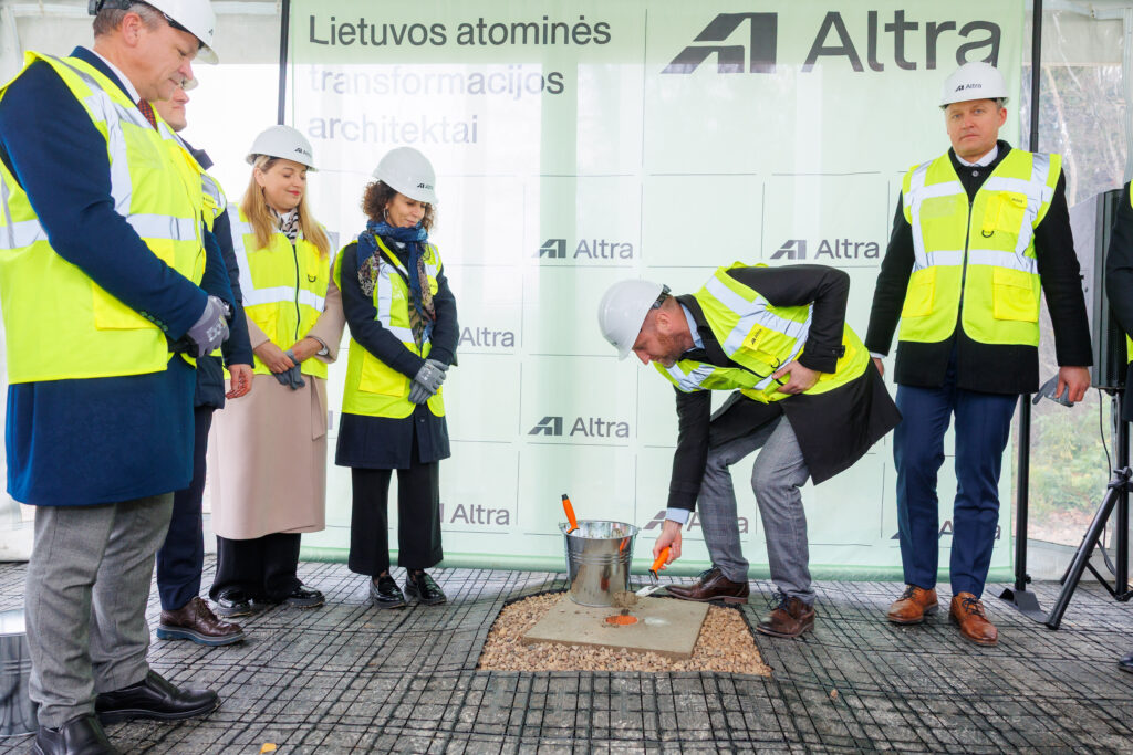 Atliekyno kapsulės įkasimo renginys, matomi įvairių organizacijų atstovai, užkasantys kapsulę