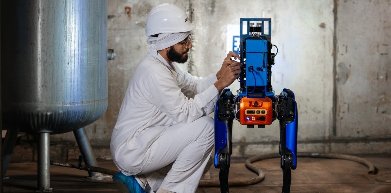 žmogus su balta apranga taiso robotą šunį